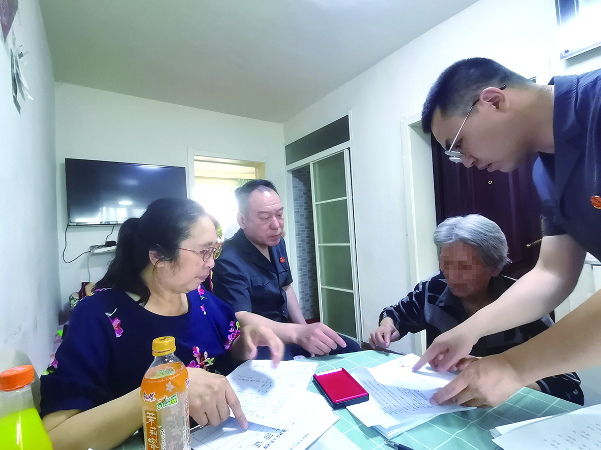 付承志（右一）胡善福（左二）指導(dǎo)潘某榮（右二）在調(diào)解書上簽字、按手印