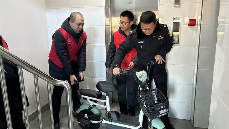 志愿者與民警一起講電動(dòng)自行車從樓道清除