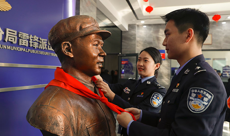 2024年3月5日，撫順市公安局望花分局雷鋒派出所民警白靜（右）和長沙市公安局雷鋒派出所民警韓政霖（左）共同為雷鋒塑像整理紅領(lǐng)巾。