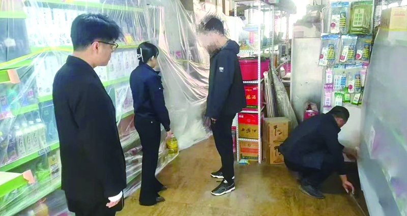 二圖，法院干警正在幫助一樓商戶粘貼防塵塑料布